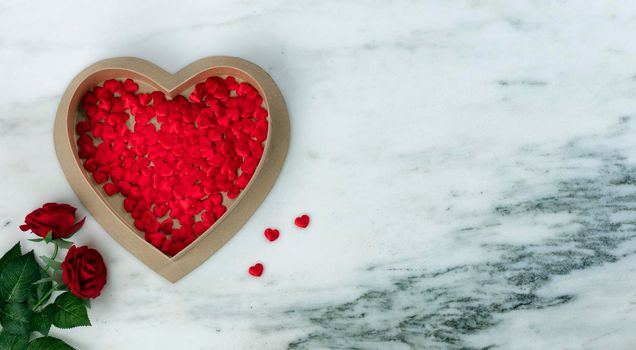 Happy Valentines Day with lovely red rose flowers plus large heart shaped giftbox filled with small hearts on natural marble stone background 