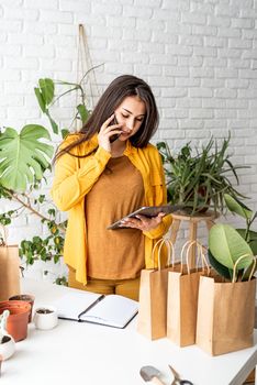 Home gardening. Small business. Woman gardener working on digital tablet and making a call