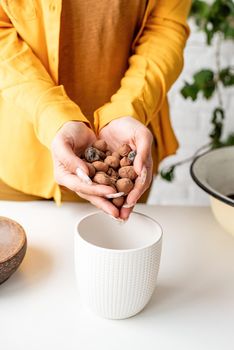 Home gardening. Woman gardener hands putting draining and soil into a new flowerpot