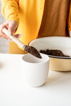 Home gardening. Woman gardener hands putting draining and soil into a new flowerpot