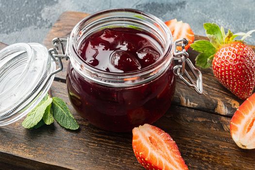 Jars of strawberry jam with berries, on gray background
