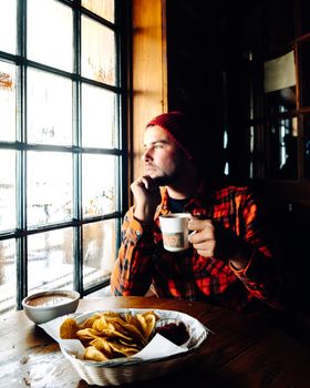 Lake Agnes Canada near Lake Louise Canada Alberta. Man looking out window dreamy look in a restaurant during winter drinking coffee or hot chocolate in a wooden cottage