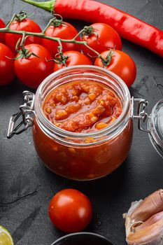 Ingredients for making tomato salsa sauce, on black background