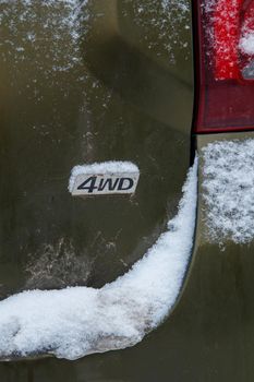 an abbreviation 4wd - four wheel drive - on dirty green car back, with snow