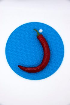 Red hot pepper pod on a blue stand.