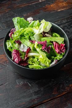 Bowls with mixed shredded salad lettuce fresh leaves, on old dark wooden table background