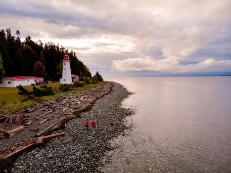 Vancouver Island, Canada, Quadra Island old historical lighthouse at Cape Mudge. couple in yellow rain coat during storm by the coast of Vancouver Island