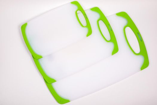 Set of white kitchen cutting boards with green handles for cooking. For cutting food, vegetables, meat, fish. Durable, professional, white plastic.