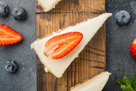 Cheesecake with blueberrie and strawberries, on gray background, top view flat lay