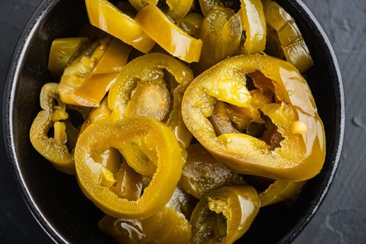 Homemade spicy jalapeno pepper marinated, on black background, top view flat lay