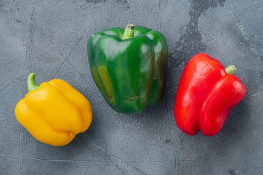 Green , yellow and red bell peppers, on gray background, top view flat lay