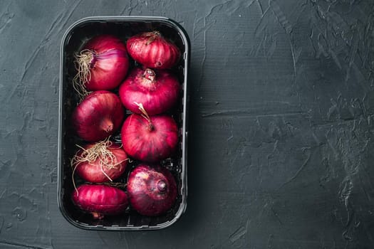 Fresh whole red onions, on black background, top view flat lay with copy space for text