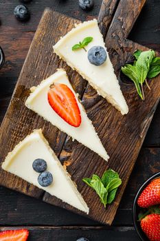 Homemade cheesecake with fresh berrie, on old dark wooden table background, top view flat lay