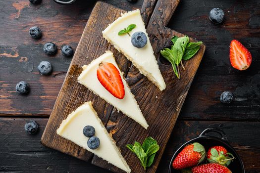 Portion of cheesecake with berrie, on old dark wooden table background, top view flat lay