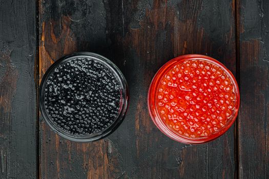 Glass jar with black and red caviar, on old dark wooden table background, top view flat lay