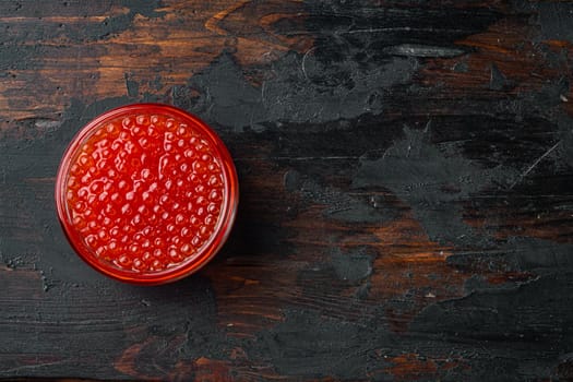 Glass with delicious red caviar, on old dark wooden table background, top view flat lay with copy space for text