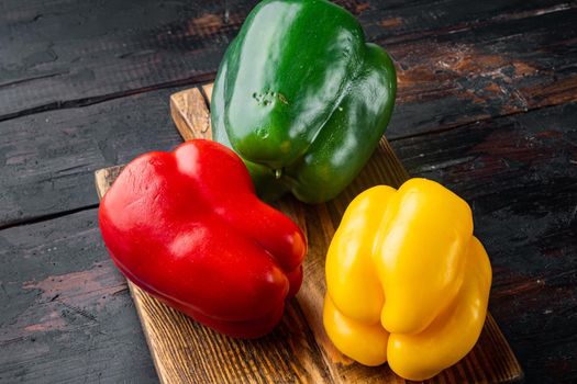 Green , yellow and red bell peppers, on old dark wooden table background