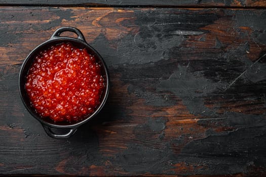 Red caviar black bowl, on old dark wooden table background, top view flat lay with copy space for text