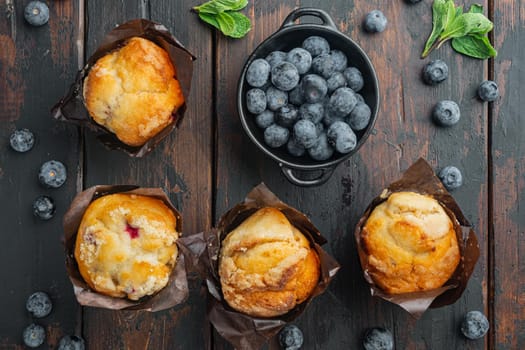 Blueberry muffins with fresh berrie, on old dark wooden table background, top view flat lay