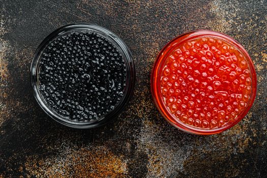 Glass jar with black and red caviar, on old dark rustic background, top view flat lay