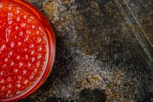 Glass with delicious red caviar, on old dark rustic background, top view flat lay with copy space for text
