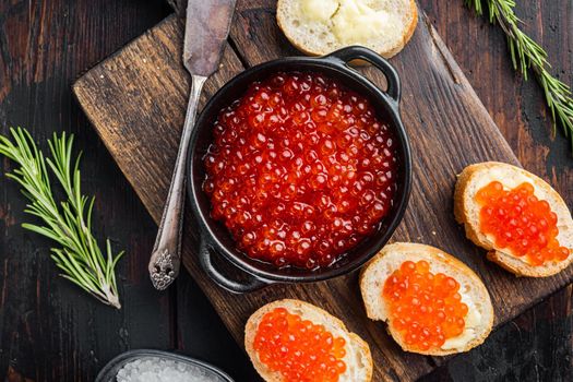 Canape toasts with red caviar, on old dark wooden table background, top view flat lay