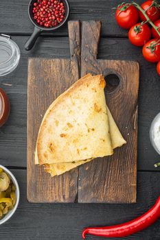 Grilled quesadillas or tortillas with cheese mix, on black wooden table background, top view flat lay