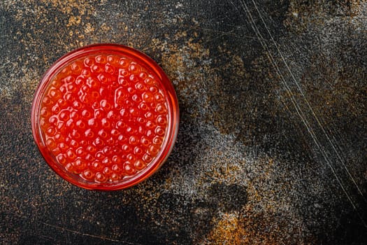 Red salmon caviar jar, on old dark rustic background, top view flat lay