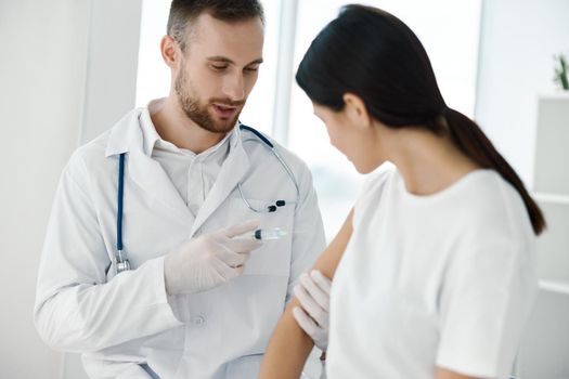 young doctor inject vaccine into patient's shoulder and syringe in hand with stethoscope laboratory. High quality photo