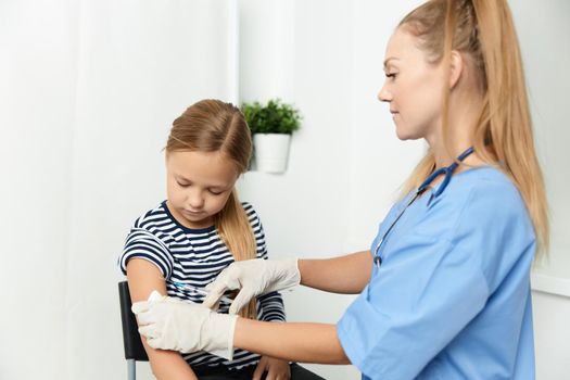 woman doctor in a blue coat injecting a child into the hand. High quality photo