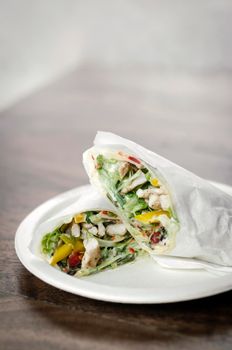 organic chicken salad wrap in white paper on wood table background