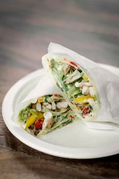 organic chicken salad wrap in white paper on wood table background