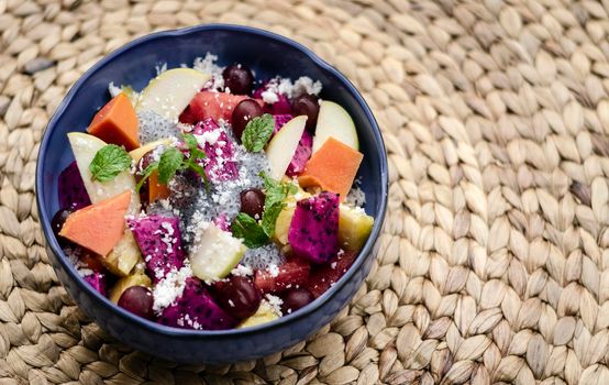 exotic mixed tropical asian fruit salad with basil seeds and coconut in bowl outdoors