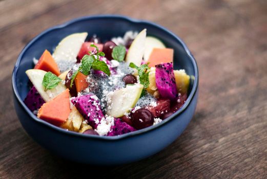 exotic mixed tropical asian fruit salad with basil seeds and coconut in bowl outdoors