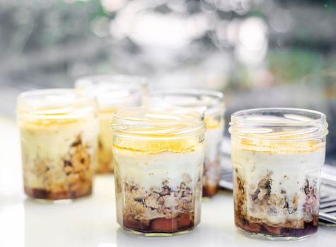 organic apple and coconut vegan cheesecake dessert in glass jam jar in cafe display