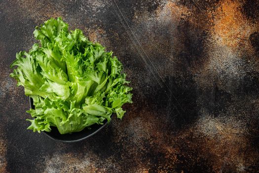Frillis lettuce leaves, on old dark rustic background, top view flat lay with copy space for text