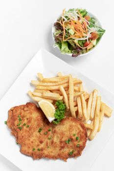 german breaded pork schnitzel with french fries on white studio background