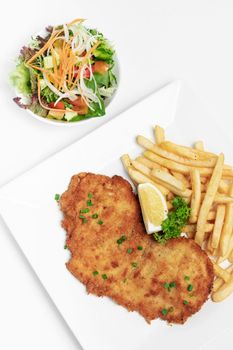 german breaded pork schnitzel with french fries on white studio background