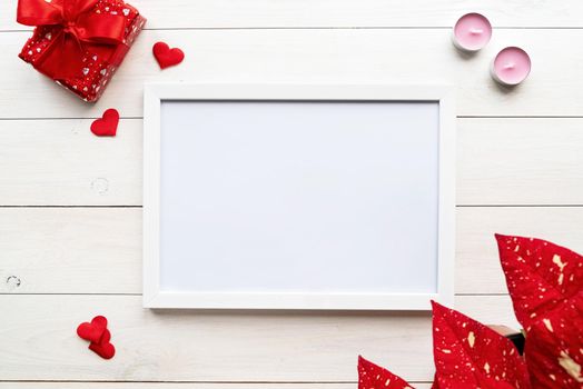 Valentines Day. White frame with valentine decorations candles, gifts and confetti top view on white wooden background
