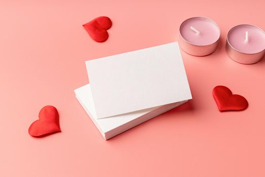 Valentines Day. Stack of visit cards on pink background with hearts and candles for mock up design