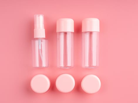 Empty plastic bottles and tubes for cosmetic on pastel pink background top view flat lay