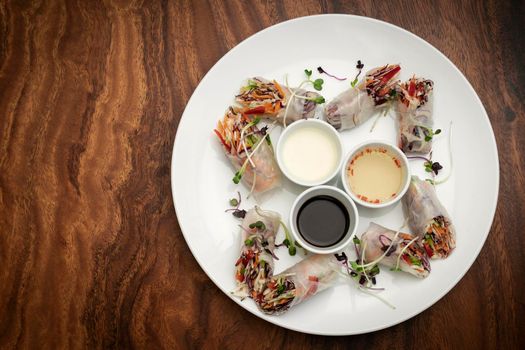 asian fresh vegetable vegan spring rolls with sauces on wood restaurant table in hanoi vietnam