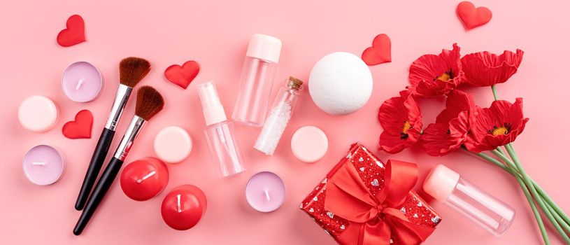 Valentines Day and Womens Day concept. Fashion cosmetic accessories with gift box, empty tubes and bottles, candles and confetti top view flat lay on pink background with copy space