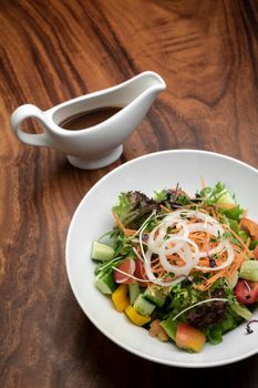 fresh organic mixed vegetable vegan Garden Salad with Vinaigrette sauce on wooden table