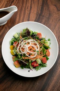 fresh organic mixed vegetable vegan Garden Salad with Vinaigrette sauce on wooden table