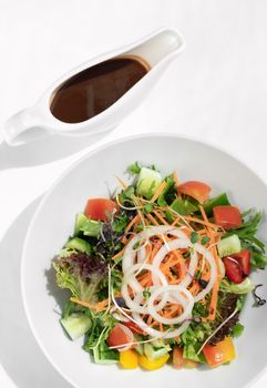 fresh organic mixed vegetable vegan Garden Salad with Vinaigrette sauce on white table