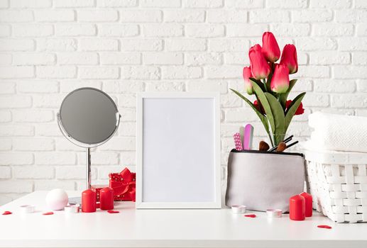 Valentines Day and Womens Day concept. cosmetic and spa accessories with gift box, flowers and candles front view on white brick wall background with copy space