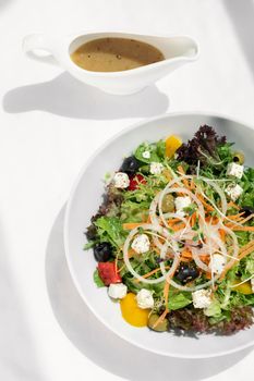 greek salad with feta cheese and olives with citrus vinaigrette on white table