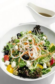 greek salad with feta cheese and olives with citrus vinaigrette on white table