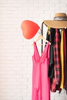 Valentines Day and Womens Day concept. Clothing rack fall of various woman clothes and pink dress for dating